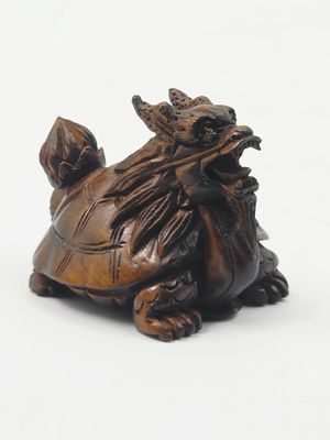 une petite statue représentant une tortue assise sur une surface blanche