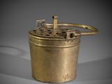 an old brass pot with a handle on a grey background