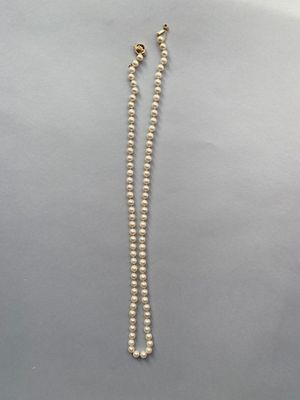 un collier de perles blanches avec un fermoir en or sur fond blanc