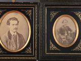 deux photographies encadrées représentant un homme et une femme, dans des cadres noirs et dorés