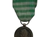 une vieille médaille avec un ruban vert sur fond blanc