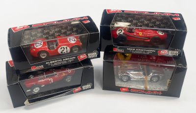trois petites voitures rouges dans leurs boîtes, posées sur une surface blanche