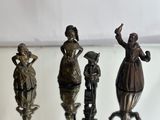 four bronze figurines of people on a glass table