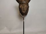 image d'un masque en bois sur un support sur fond blanc