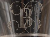 a glass with a monogram on it sitting on a table