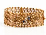 un gros plan d'un bracelet en or orné de pierres bleues sur fond blanc