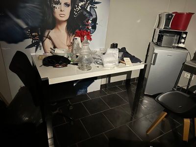 une pièce faiblement éclairée, avec une table, des chaises et un tableau accroché au mur
