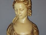 a statue of a woman with braid hair on a wooden stand
