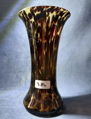 un vase marron et noir, muni d'une étiquette, posé sur un tissu bleu
