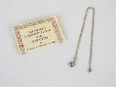 un collier orné d'une pierre violette, à côté d'un certificat