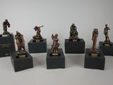 six figurines de soldats en bronze posées sur des socles, sur une surface blanche