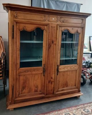 une vieille armoire en bois avec des portes vitrées dans une pièce