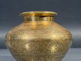 a gold vase sitting on a table with a gray background