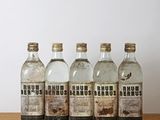 Quatre bouteilles de gin sont alignées sur une table en bois
