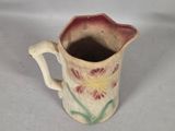 a small pitcher with a flower design on it