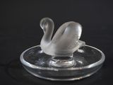 a glass swan sitting on top of a glass plate