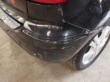the rear end of a black car with a denting bumper