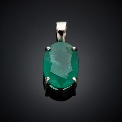 un pendentif en émeraude de taille ovale, serti à la main, sur fond noir