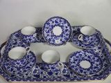 une assiette bleue et blanche sur laquelle sont posées des tasses et des soucoupes