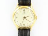 une montre-bracelet en or avec un cadran blanc et un bracelet noir