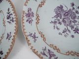 two plates with purple flowers on them sitting on a table