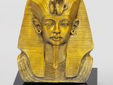 a gold statue of an egyptian pharaoh on a black base