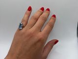 a woman ' s hand with red nails and a ring on her finger