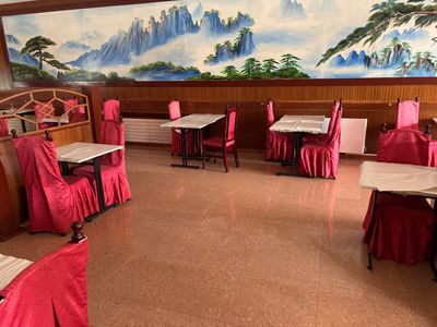 de nombreuses tables et chaises dans un restaurant où est accrochée une peinture au mur
