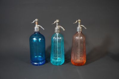 three bottles with soap and lotion on a gray surface