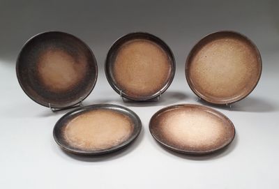 four brown plates sitting next to each other on a white surface