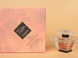 un petit flacon de parfum posé à côté d'une boîte rose