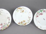 trois assiettes ornées d'oiseaux et de fleurs, posées sur une table