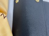 a black purse and a yellow tie on a white table