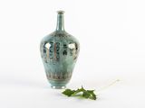 un petit vase avec une feuille par terre