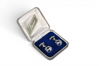 a pair of cufflinks in a silver case with blue velvet lining