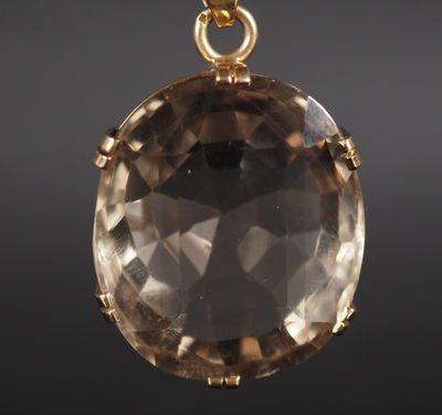 un gros plan d'un pendentif plaqué or orné d'un gros quartz fumé facetté