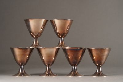 six copper goblets are lined up in a pyramid on a white surface