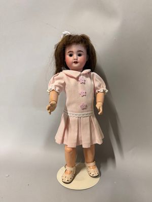 un gros plan sur une poupée aux cheveux bruns et vêtue d'une robe rose