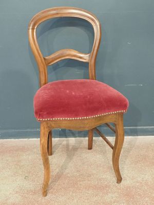 an old wooden chair with red velvet upholstered seat