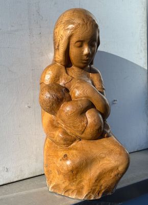 une statue représentant une femme tenant un bébé sur un rebord