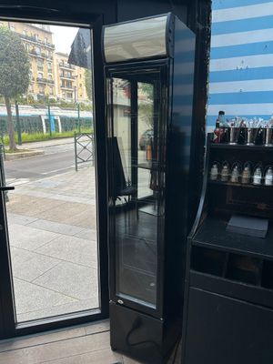 un réfrigérateur noir posé devant une porte vitrée