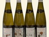 four bottles of wine are lined up on a white surface