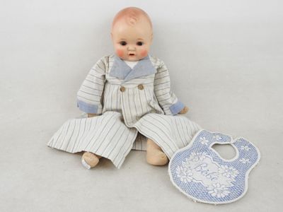 une poupée assise à côté d'un bavoir, bavoir, bavoir, bavoir, bavoir, bavoir, bavoir, bavoir, bavoir, bavoir, b
