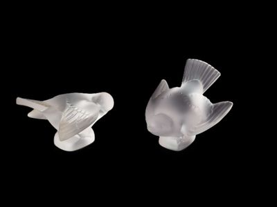 deux oiseaux en verre assis l'un à côté de l'autre sur un fond noir