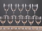 many wine glasses lined up on a wooden table