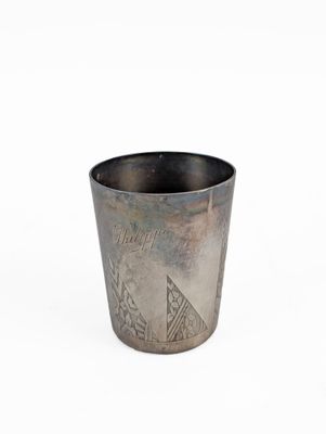an old silver cup sitting on top of a white surface
