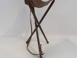 une image représentant un petit tabouret avec deux pieds en bois et une assise en cuir