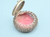 an image of a small gold locke with a pink glass inside