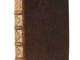 an old brown book with gold trim sitting on top of a white surface