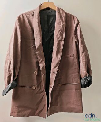 une veste marron suspendue à un cintre accroché au mur